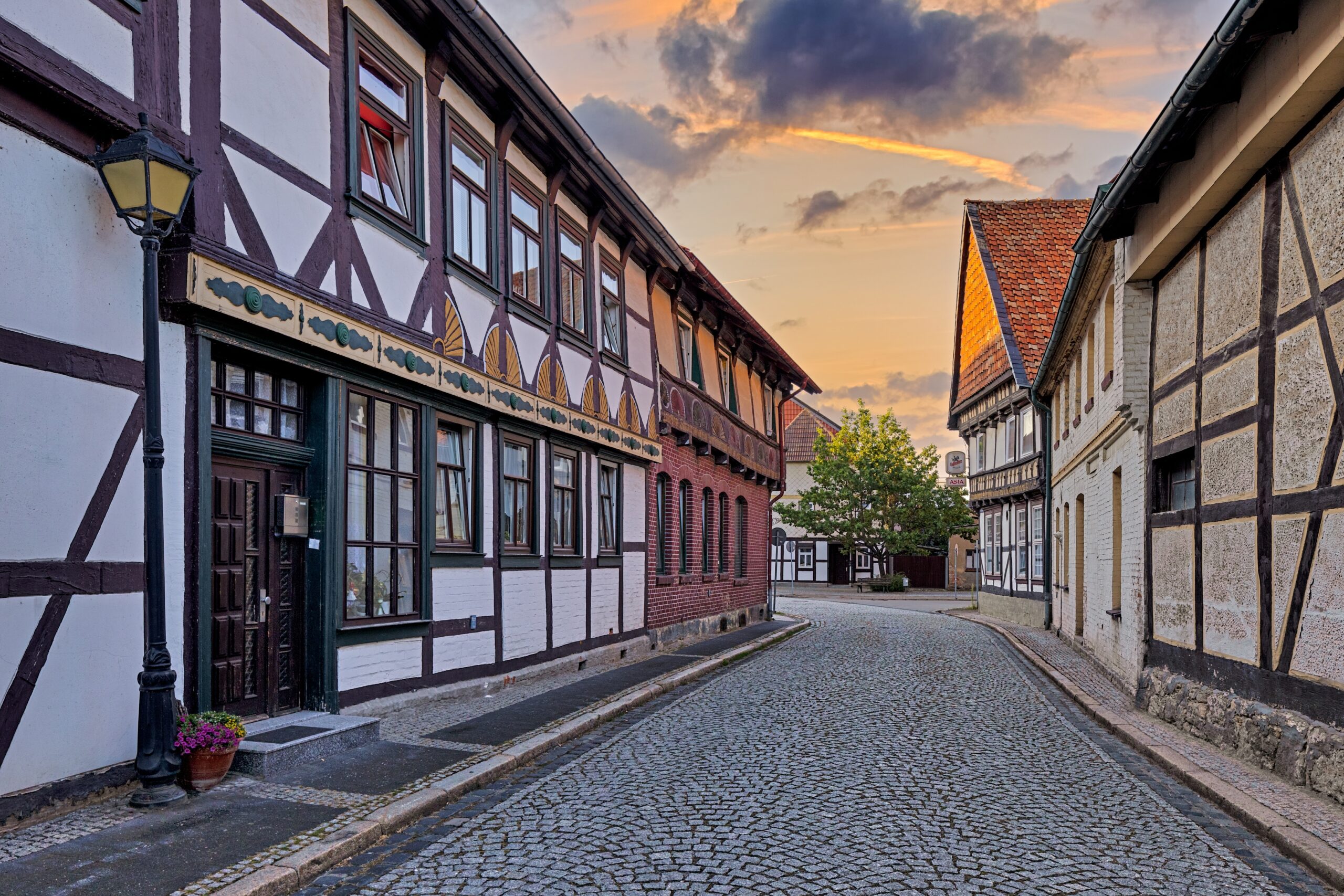 Charmante Altstadtstraße mit Fachwerkhäusern und gepflastertem Boden, umgeben von malerischen Wolken am Abendhimmel. Ideal für Spaziergänge und Fotomotive.