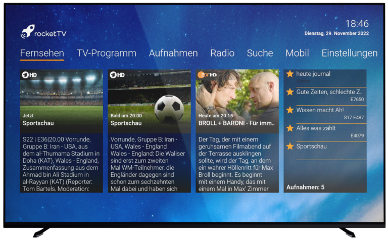 Fernseher mit dem RocketTV Interface, das aktuelle TV-Programme, Aufnahmen und Radiosender anzeigt. Der Bildschirm zeigt eine Sportschau, die Gruppenphase eines Fußballturniers sowie eine Sendung namens "BROLL & BARONI". Datum: 29. November 2022.
